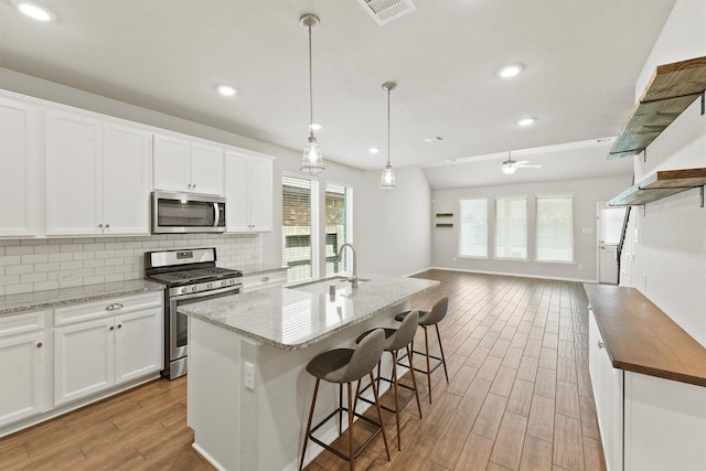 4430 Lone Alcove Dr, Spring, TX 77386 - kitchen with appliances with stainless steel finishes, a sink, light wood-style flooring, backsplash, and open floor plan