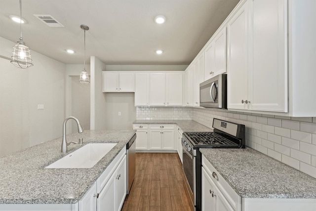 4430 Lone Alcove Dr, Spring, TX 77386 - kitchen featuring stainless steel appliances, a sink, dark wood-type flooring, white cabinetry, and decorative light fixtures