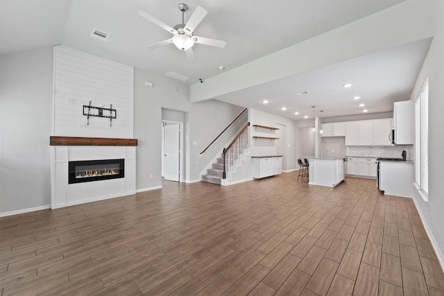 4430 Lone Alcove Dr, Spring, TX 77386 - unfurnished living room featuring stairway, wood finished floors, lofted ceiling, a ceiling fan, and a large fireplace
