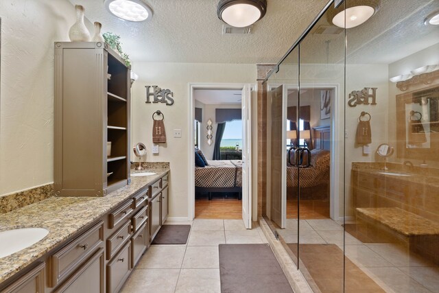2117 Gunwale Cir, Willis, TX 77318 - bathroom featuring ensuite bathroom, a stall shower, a textured ceiling, double vanity, and tile patterned floors