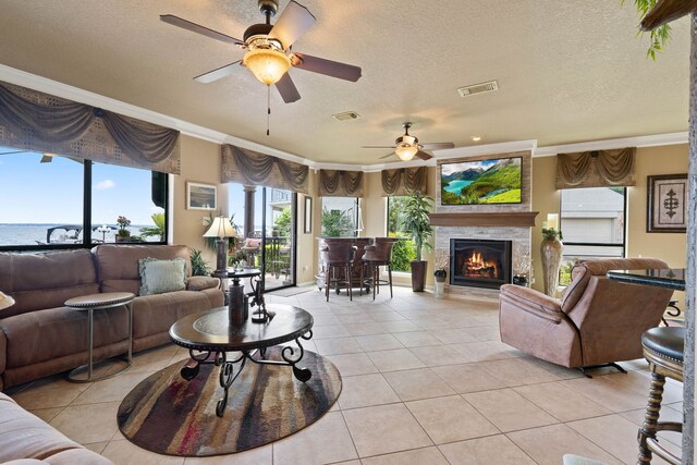 2117 Gunwale Cir, Willis, TX 77318 - living room featuring ornamental molding, a ceiling fan, light tile patterned flooring, a lit fireplace, and a textured ceiling
