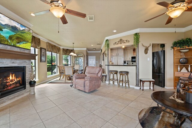 2117 Gunwale Cir, Willis, TX 77318 - living area featuring ceiling fan, ornamental molding, light tile patterned flooring, baseboards, and a stone fireplace