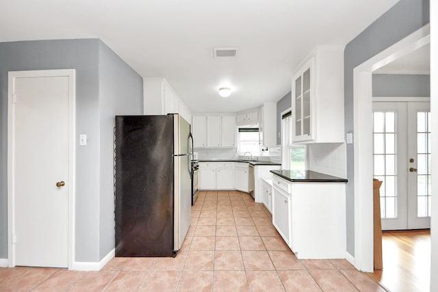 1831 Watercrest Dr, Houston, TX 77008 - kitchen with freestanding refrigerator, dark countertops, a sink, light tile patterned floors, and white cabinets