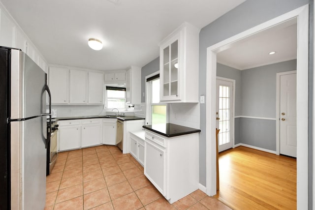 1831 Watercrest Dr, Houston, TX 77008 - kitchen featuring appliances with stainless steel finishes, a sink, dark countertops, glass insert cabinets, and white cabinetry