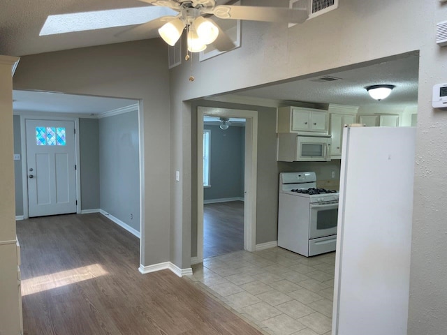 5311 Gano St, Houston, TX 77009 - kitchen featuring white appliances, ceiling fan, light wood-style flooring, white cabinets, and baseboards