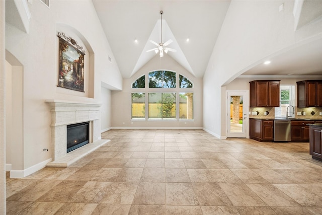 6014 Shady Birch Holw, Houston, TX 77345 - unfurnished living room featuring a ceiling fan, a glass covered fireplace, baseboards, high vaulted ceiling, and a sink