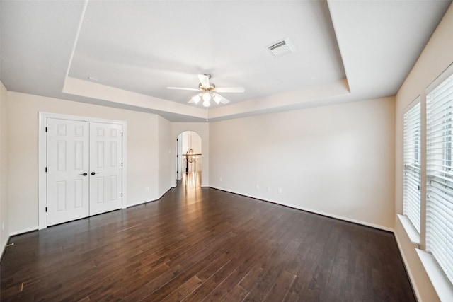 6014 Shady Birch Holw, Houston, TX 77345 - unfurnished bedroom featuring a raised ceiling, arched walkways, dark wood-style floors, and ceiling fan