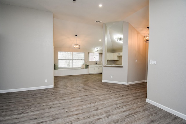 2012 Hickory Glen Dr, Missouri City, TX 77489 - unfurnished living room with a chandelier, lofted ceiling, wood finished floors, baseboards, and a sink