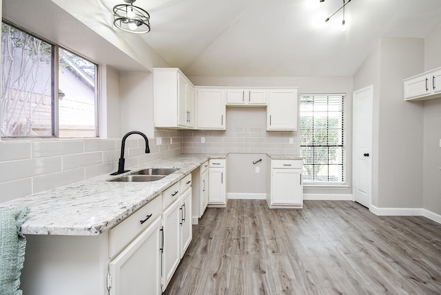 2012 Hickory Glen Dr, Missouri City, TX 77489 - kitchen featuring a sink, lofted ceiling, light stone counters, light wood-type flooring, and white cabinets