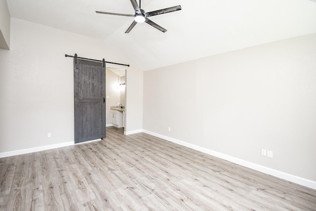 2012 Hickory Glen Dr, Missouri City, TX 77489 - unfurnished bedroom with a barn door, light wood finished floors, lofted ceiling, baseboards, and connected bathroom