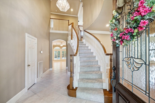 1615 Lake Wilderness Ln, Kingwood, TX 77345 - entryway featuring tile patterned flooring, a high ceiling, stairs, baseboards, and crown molding