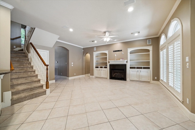 1615 Lake Wilderness Ln, Kingwood, TX 77345 - unfurnished living room featuring ceiling fan, arched walkways, ornamental molding, light tile patterned floors, and built in shelves