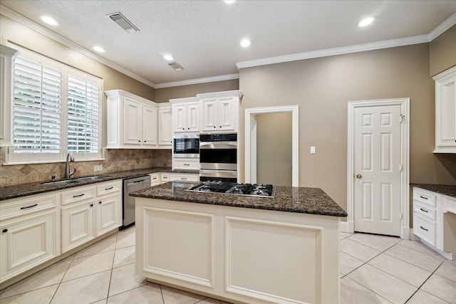 1615 Lake Wilderness Ln, Kingwood, TX 77345 - kitchen with stainless steel appliances, a sink, light tile patterned floors, a kitchen island, and ornamental molding