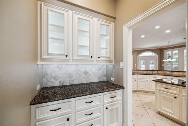 1615 Lake Wilderness Ln, Kingwood, TX 77345 - kitchen featuring decorative backsplash, dark stone counters, light tile patterned flooring, and white cabinets