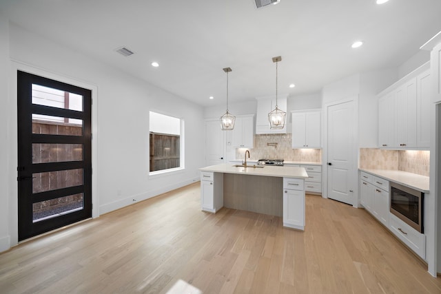 224 W 23rd St Unit B, Houston, TX 77008 - kitchen with stainless steel microwave, a sink, light countertops, light wood finished floors, and backsplash