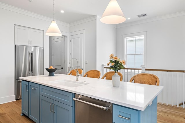 2604 E Seaside Dr, Galveston, TX 77550 - kitchen featuring stainless steel appliances, blue cabinetry, a sink, light wood-type flooring, and crown molding