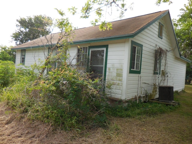 628 Austin St W, Matagorda, TX 77457 - view of side of property featuring roof with shingles and central AC