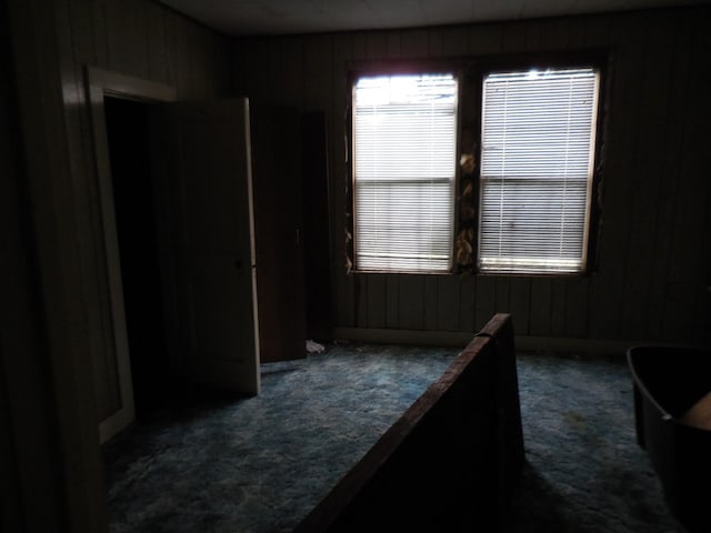 628 Austin St W, Matagorda, TX 77457 - unfurnished bedroom featuring carpet and wood walls