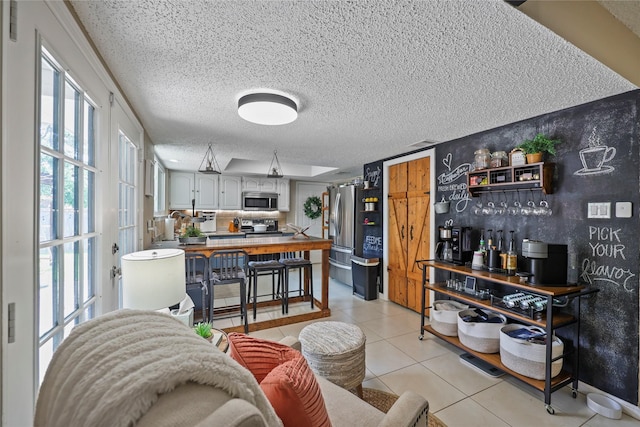 23910 Spring Day Ln, Spring, TX 77373 - kitchen featuring appliances with stainless steel finishes, a textured ceiling, light tile patterned floors, and a peninsula