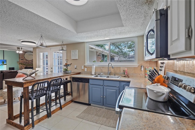 23910 Spring Day Ln, Spring, TX 77373 - kitchen with appliances with stainless steel finishes, a sink, blue cabinetry, light countertops, and a textured ceiling