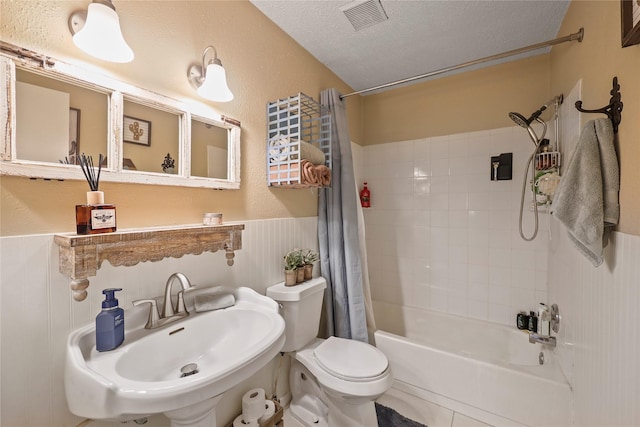 23910 Spring Day Ln, Spring, TX 77373 - bathroom featuring shower / bath combo with shower curtain, toilet, a sink, a textured ceiling, and wainscoting
