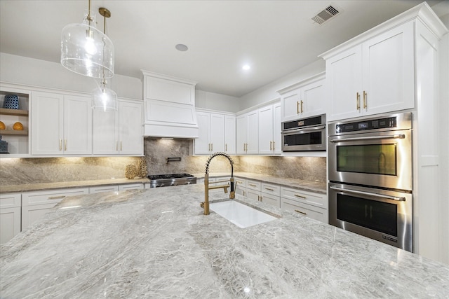 19 Sanctuary Trl, Missouri City, TX 77459 - kitchen with stainless steel double oven, open shelves, white cabinets, decorative backsplash, and range