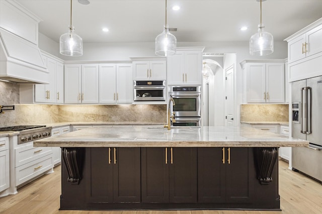 19 Sanctuary Trl, Missouri City, TX 77459 - kitchen featuring stainless steel appliances, white cabinets, custom range hood, an island with sink, and recessed lighting