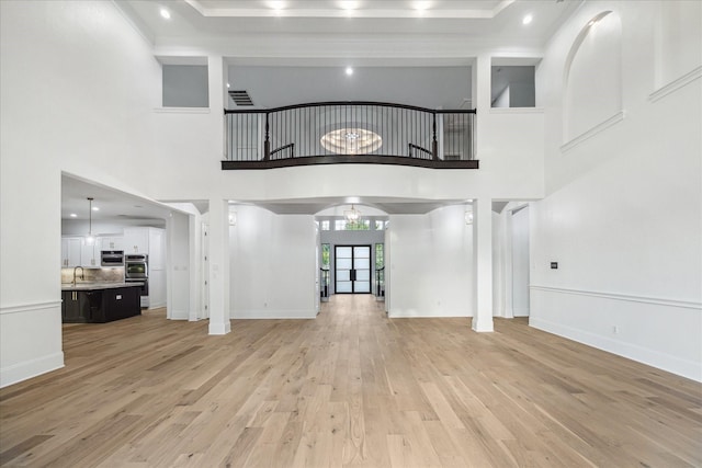 19 Sanctuary Trl, Missouri City, TX 77459 - unfurnished living room with light wood-style floors, a high ceiling, arched walkways, and ornamental molding