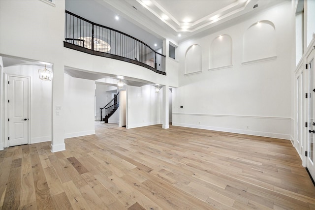 19 Sanctuary Trl, Missouri City, TX 77459 - unfurnished living room featuring light wood-style floors, stairs, a towering ceiling, and a tray ceiling