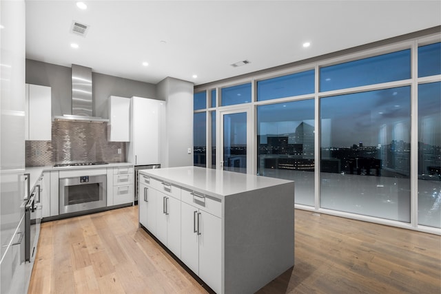 4521 San Felipe St Unit 2601, Houston, TX 77027 - kitchen with oven, wall chimney exhaust hood, modern cabinets, light wood finished floors, and a center island