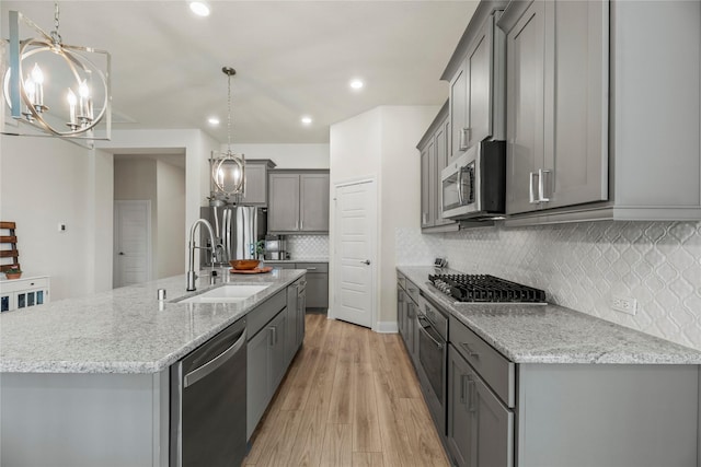 29510 Enchanted Breeze Ln, Katy, TX 77494 - kitchen featuring stainless steel appliances, a chandelier, gray cabinets, a sink, and light stone countertops