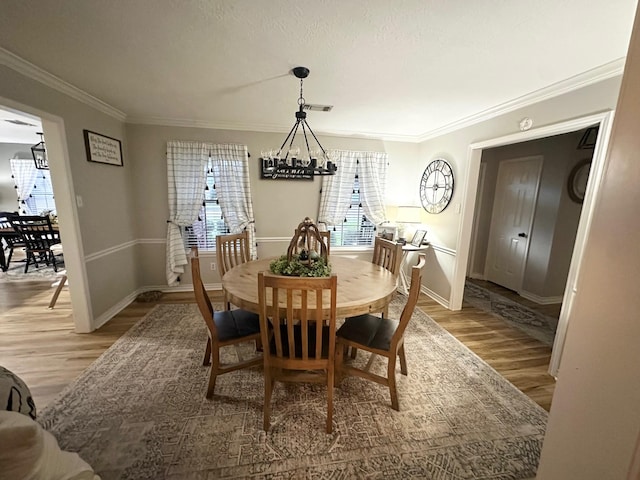 1308 Hagan St, Crockett, TX 75835 - dining space with light wood-type flooring, crown molding, baseboards, and a chandelier