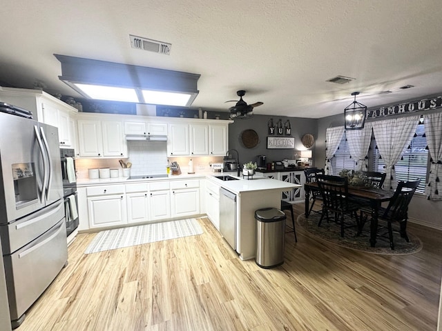 1308 Hagan St, Crockett, TX 75835 - kitchen with appliances with stainless steel finishes, a peninsula, light wood-type flooring, ceiling fan, and white cabinetry