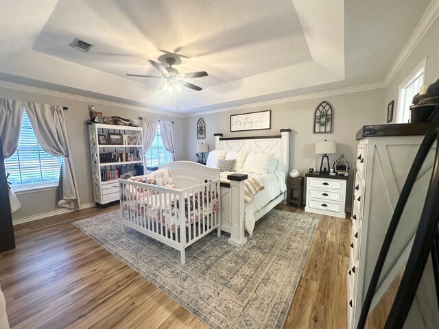 1308 Hagan St, Crockett, TX 75835 - bedroom with a raised ceiling, multiple windows, wood finished floors, a ceiling fan, and ornamental molding