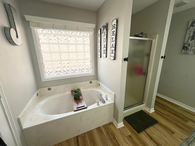 1308 Hagan St, Crockett, TX 75835 - bathroom with wood finished floors, a stall shower, a bath, and baseboards