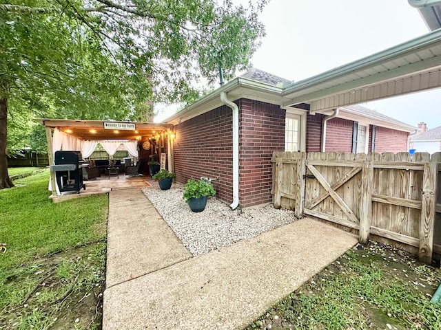 1308 Hagan St, Crockett, TX 75835 - view of side of property with brick siding, a patio, outdoor lounge area, and a gate