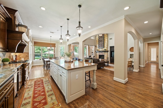 77 Big Trl, Missouri City, TX 77459 - kitchen featuring a stone fireplace, dark wood finished floors, a kitchen bar, crown molding, and recessed lighting