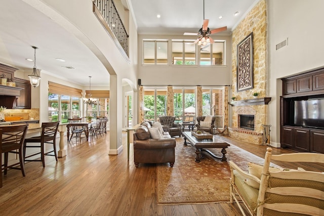 77 Big Trl, Missouri City, TX 77459 - living room featuring a fireplace, wood finished floors, arched walkways, ceiling fan, and a high ceiling