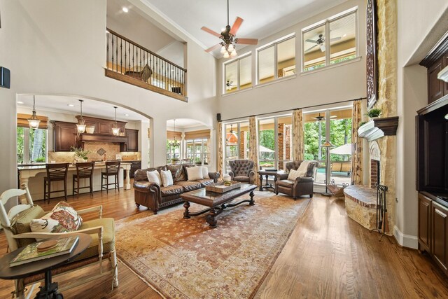 77 Big Trl, Missouri City, TX 77459 - living area with ceiling fan, arched walkways, a fireplace with raised hearth, a towering ceiling, and wood finished floors