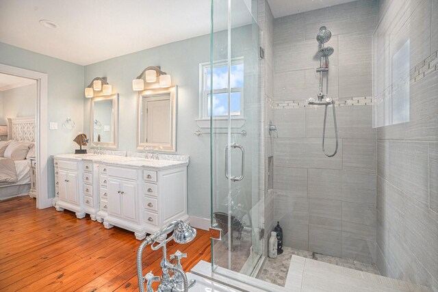 1401 103rd St, Galveston, TX 77554 - bathroom featuring tiled shower, wood-type flooring, double vanity, baseboards, and ensuite bath