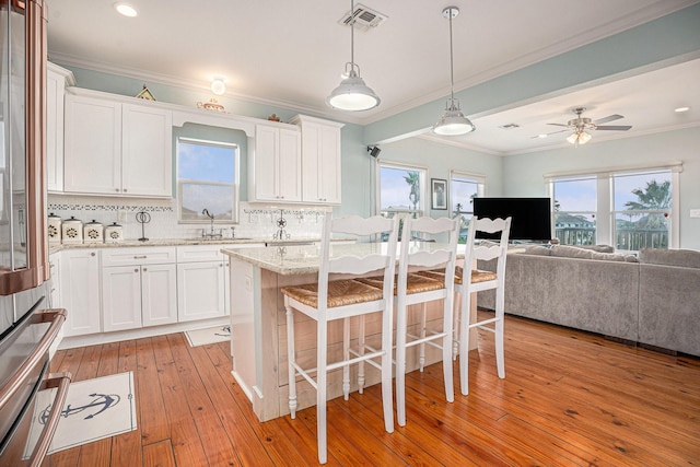 1401 103rd St, Galveston, TX 77554 - kitchen featuring a sink, a kitchen breakfast bar, white cabinetry, open floor plan, and ornamental molding