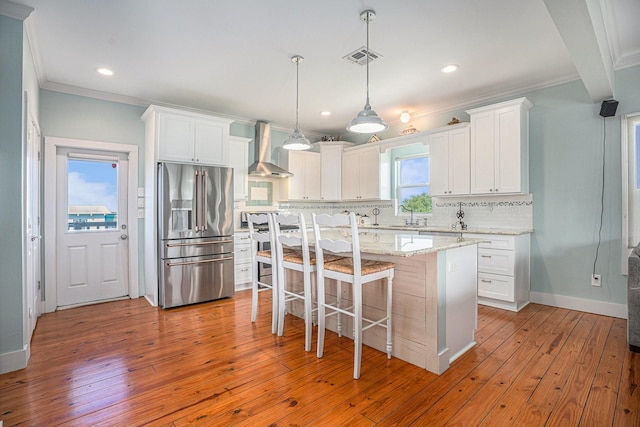 1401 103rd St, Galveston, TX 77554 - kitchen featuring stainless steel fridge with ice dispenser, wall chimney range hood, tasteful backsplash, crown molding, and hardwood / wood-style floors