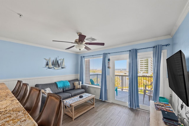 9520 Seawall Blvd Unit 338, Galveston, TX 77554 - living room featuring crown molding, a ceiling fan, light wood finished floors, and a wainscoted wall