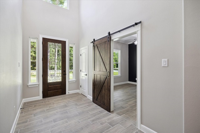 26800 Saddle Horn, Waller, TX 77484 - entrance foyer with baseboards, healthy amount of natural light, a barn door, light wood-style floors, and a high ceiling