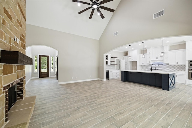 26800 Saddle Horn, Waller, TX 77484 - unfurnished living room featuring a ceiling fan, a large fireplace, high vaulted ceiling, arched walkways, and baseboards