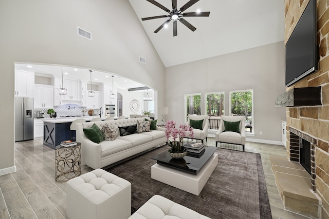 26800 Saddle Horn, Waller, TX 77484 - living room featuring high vaulted ceiling, a ceiling fan, light wood finished floors, a fireplace with raised hearth, and arched walkways