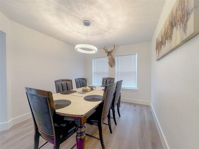 18323 River Sage Dr, Houston, TX 77084 - dining room with light wood finished floors, a chandelier, baseboards, and a textured ceiling