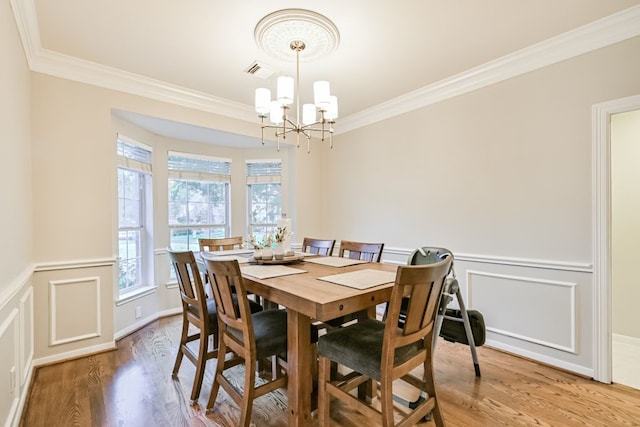 2803 Canyon Dr, Pearland, TX 77584 - dining area featuring crown molding, a chandelier, a decorative wall, light wood-style flooring, and a wainscoted wall