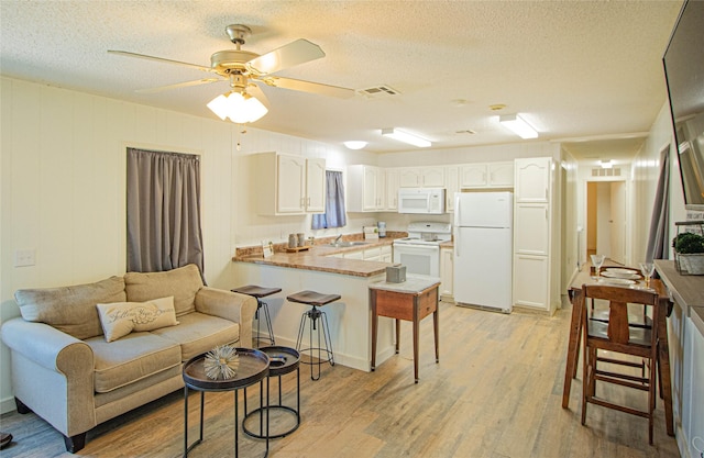 277 Lucy, Livingston, TX 77351 - kitchen featuring white appliances, a peninsula, a sink, light wood finished floors, and white cabinetry