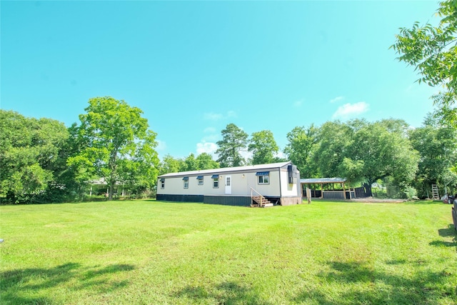 277 Lucy, Livingston, TX 77351 - view of grassy yard with entry steps, a carport, and view of wooded area